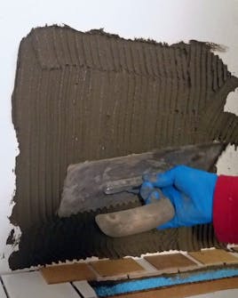 Bordplade med fliser: fliseklæberen smøres på væggen Bordplade med fliser: fliseklæberen smøres på væggen